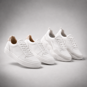 Two pairs of white trainers on a grey background